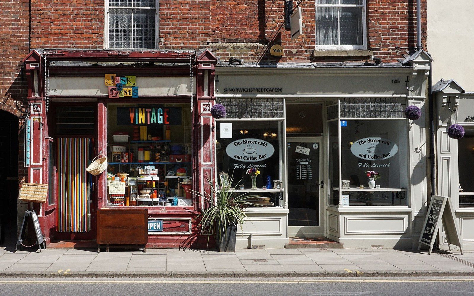 A vintage shop and street cafe with coffee bar sit side by side on a brick storefront