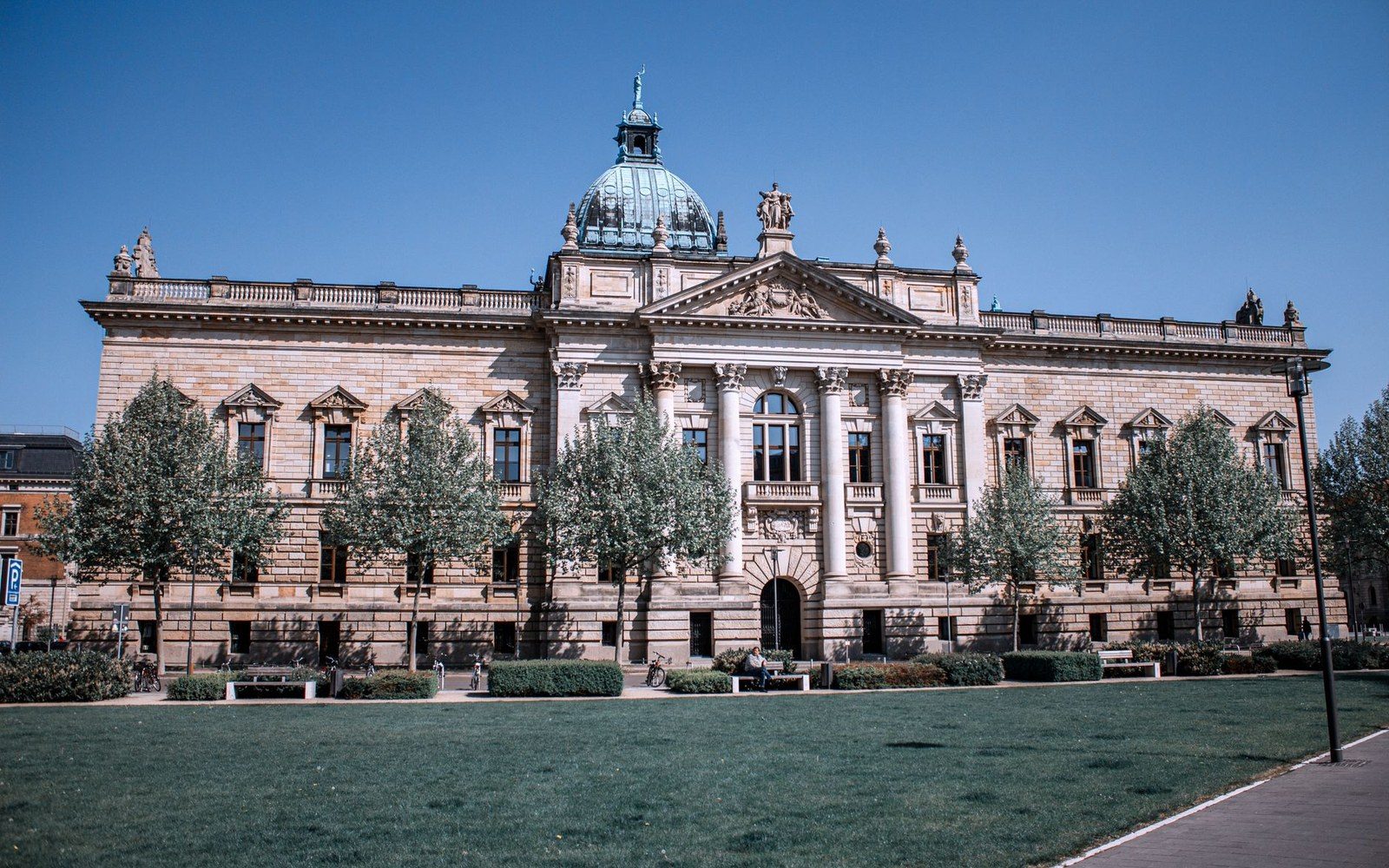 Domed neoclassical courthouse with columned portico, flanked by trees and a lawn